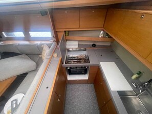 A compact kitchenette with a stove, sink, and storage cabinets. - Sun-Kissed Sailing Adventure in Islas Cícladas, Mykonos (Mykonos)