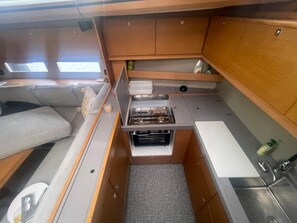 A compact kitchenette with a stove, sink, and storage cabinets. - Sun-Kissed Sailing Adventure in Islas Cícladas, Mykonos (Mykonos)