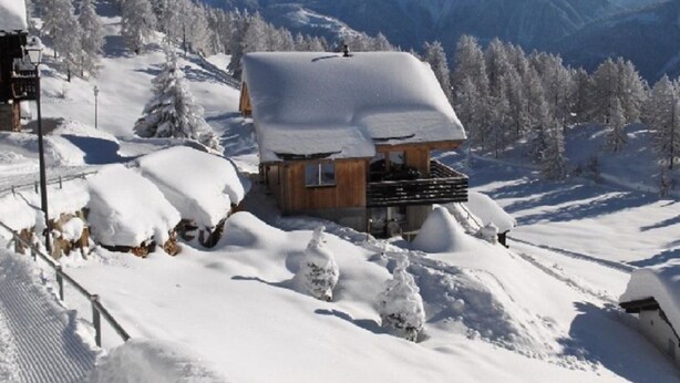 A wooden chalet with a snow-covered roof, surrounded by snow-covered trees and mountains in the background. - Amiel EG Süd Appartement/Fewo, Dusche und Bad, WC 3 1/2 Zimmerwohnung, 5-Betten by Interhome (Riederalp)