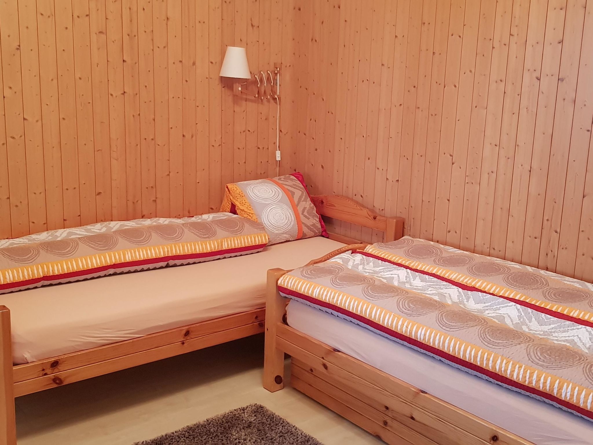 A room with two wooden bunk beds, each with a patterned bedspread and pillows.
