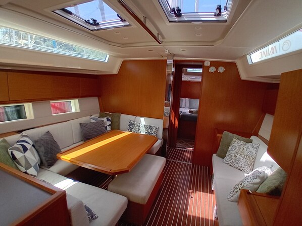 A compact interior with a sofa, a table, and a narrow passageway leading to a bedroom. - Sun-Kissed Sailing Adventure in the Ionian Islands (Vlicho)