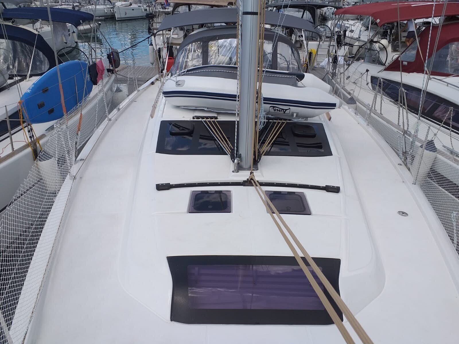 Una marina con barcos amarrados, un velero blanco y un barco azul con zona cubierta.
