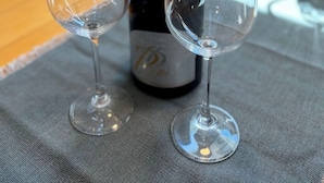 Een fles wijn en twee lege wijnglazen op een tafel.