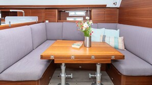 A boat interior with a wooden table, cushioned seating, and a metal sink. - Sun-Kissed Sailing Adventure in Sibenik, Croatia (Primošten)