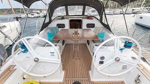 A boat's deck with two steering wheels, a central table, and a covered area. - Sun-Kissed Sailing Adventure in Sibenik, Croatia (Primošten)