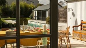 En matplats med utsikt över en swimmingpool, utomhusmöbler och ett hus i bakgrunden.