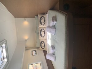 Ein Zimmer mit einem Bett, einem Fenster und einem kleinen Tisch mit einer Lampe.
