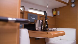 A compact kitchen area with a Raymarine navigation device, a stainless steel kettle, a wine bottle, and a small glass on a wooden countertop. - Sun-Kissed Sailing Adventure in the Saronic Islands (Kallithea)