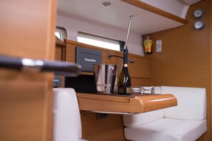 Eine kleine Küchenzeile mit Raymarine Navigationsgerät, Edelstahl-Wasserkocher, einer Weinflasche und einem kleinen Glas auf einer Holzauskład.
