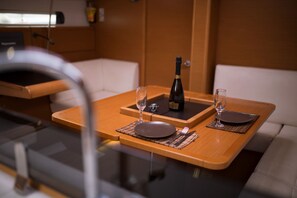 Une table à manger avec deux assiettes, des couverts et des verres, une bouteille de champagne et un banc en bois.