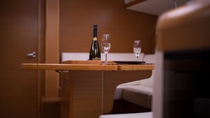 A wooden table with a bottle and two glasses, a door, and a bed. - Sun-Kissed Sailing Adventure in the Saronic Islands (Kallithea)