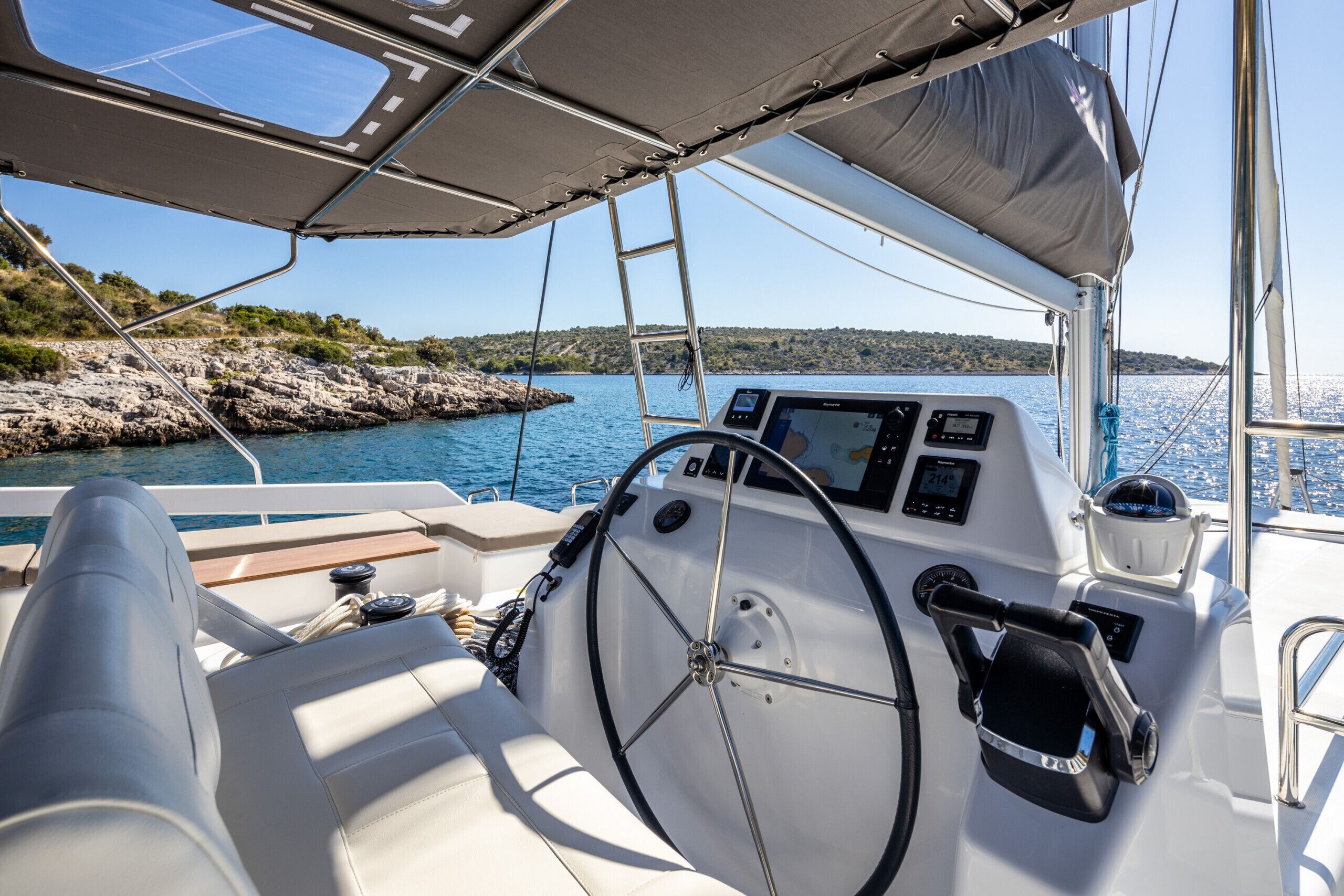 A boat's interior with a steering wheel, control panel, and seating area.
