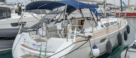 A sailboat docked at a marina with a covered deck, a name 'SUN ODYSSEY,' and a visible cabin structure.