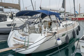 A sailboat docked at a marina with a covered deck, a name 'SUN ODYSSEY,' and a visible cabin structure.