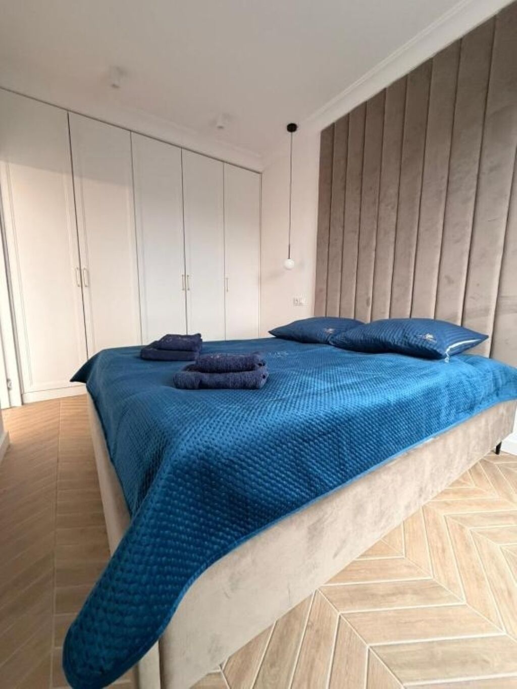 A bedroom with a bed, wooden panel wall, and a wardrobe.