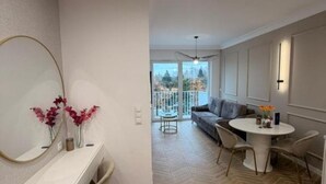A modern interior with a white console, a round dining table, and a grey sofa.