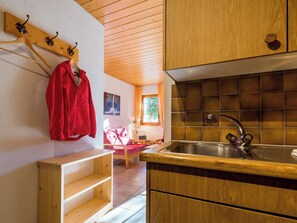 Eine kleine Küche mit Holzausstattung, einem Edelstahlspülbecken und einem Holzregal.