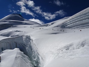 Un paysage enneigé avec un glacier et un groupe de personnes en randonnée.