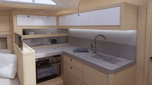 A compact kitchen with a built-in oven, a sink, and storage cabinets. - Sun-Kissed Sailing Adventure in the Dodecanese Islands (Rodos)