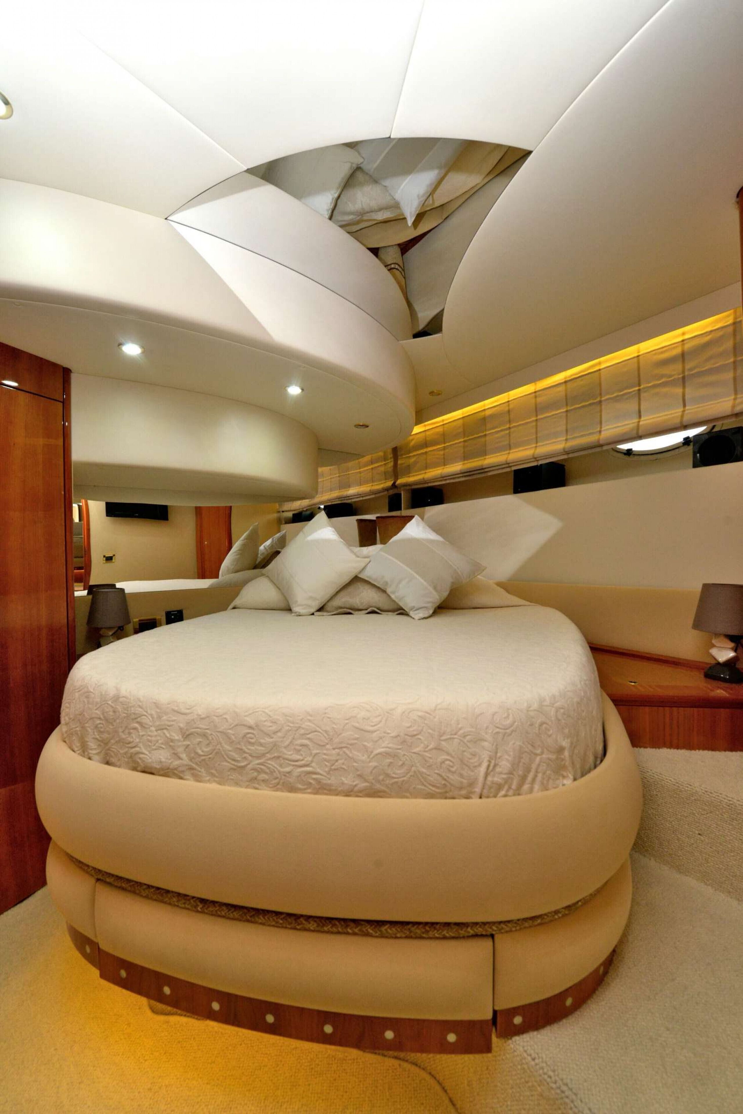 Una cama redonda con cabecera curva, una mesita de noche y una lámpara de pared.