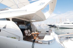 A yacht with a covered deck area, seating arrangements, and a view of other boats in the marina.