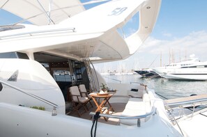 A yacht with a covered deck area, seating arrangements, and a view of other boats in the marina. - Sun-Kissed Sailing Adventure in Islas Sarónicas (Alimos)