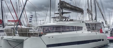 A white yacht named 'BALI' docked at a marina with other boats.