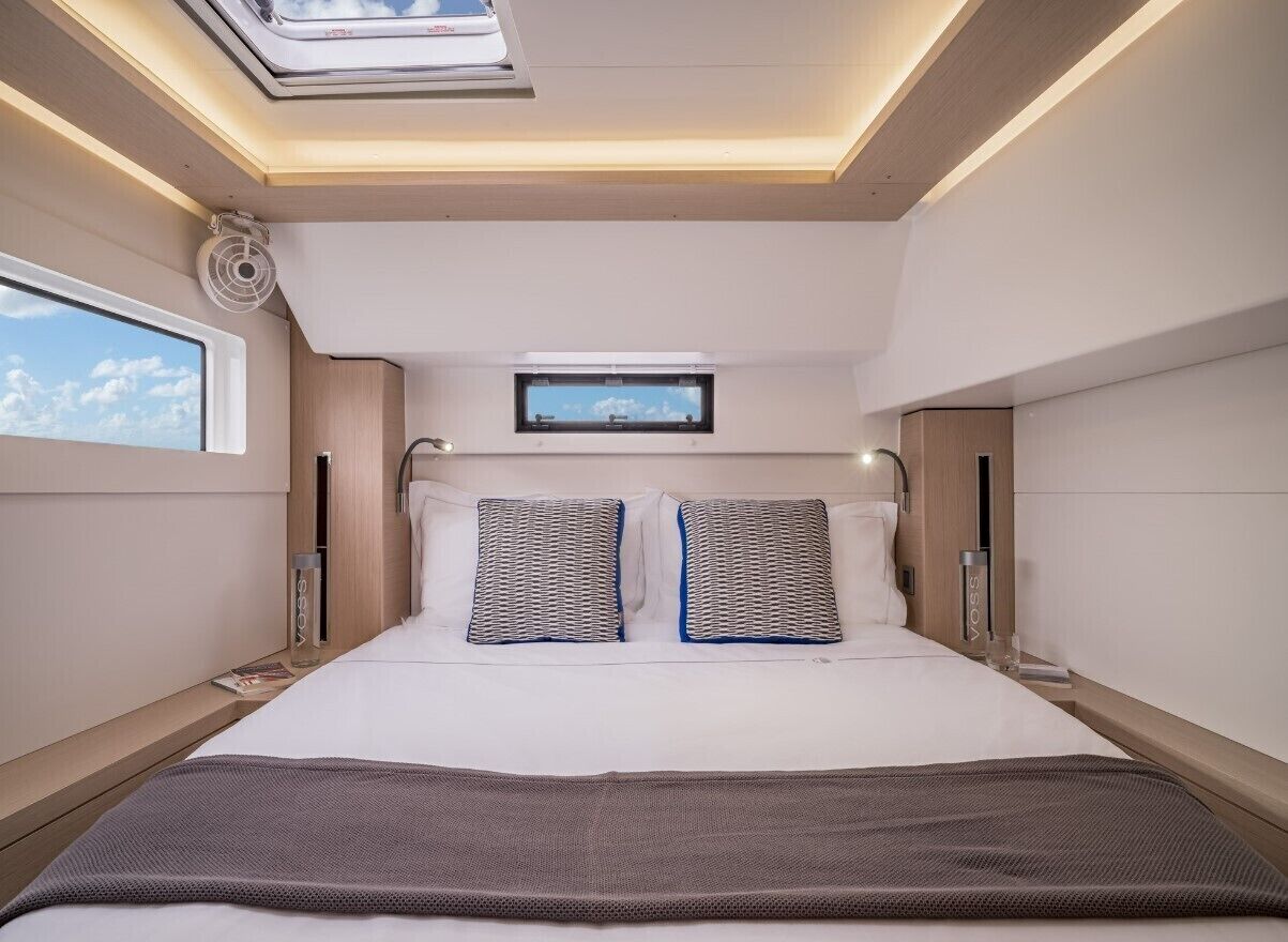Une chambre d’hôtel moderne dotée d’une lucarne, d’un téléviseur à écran plat et d’un lit agrémenté d’oreillers à motifs.