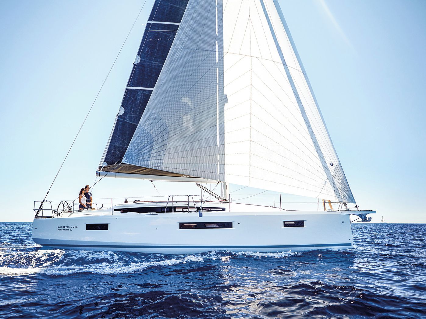 Eine Segelyacht mit weißem Rumpf und großem Segel fährt auf dem Wasser.