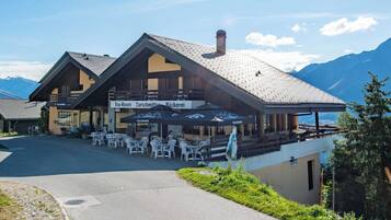 A mountain lodge with outdoor seating and a view of the mountains.