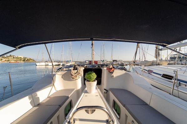 A boat deck with a potted plant, seating, and a view of the marina.