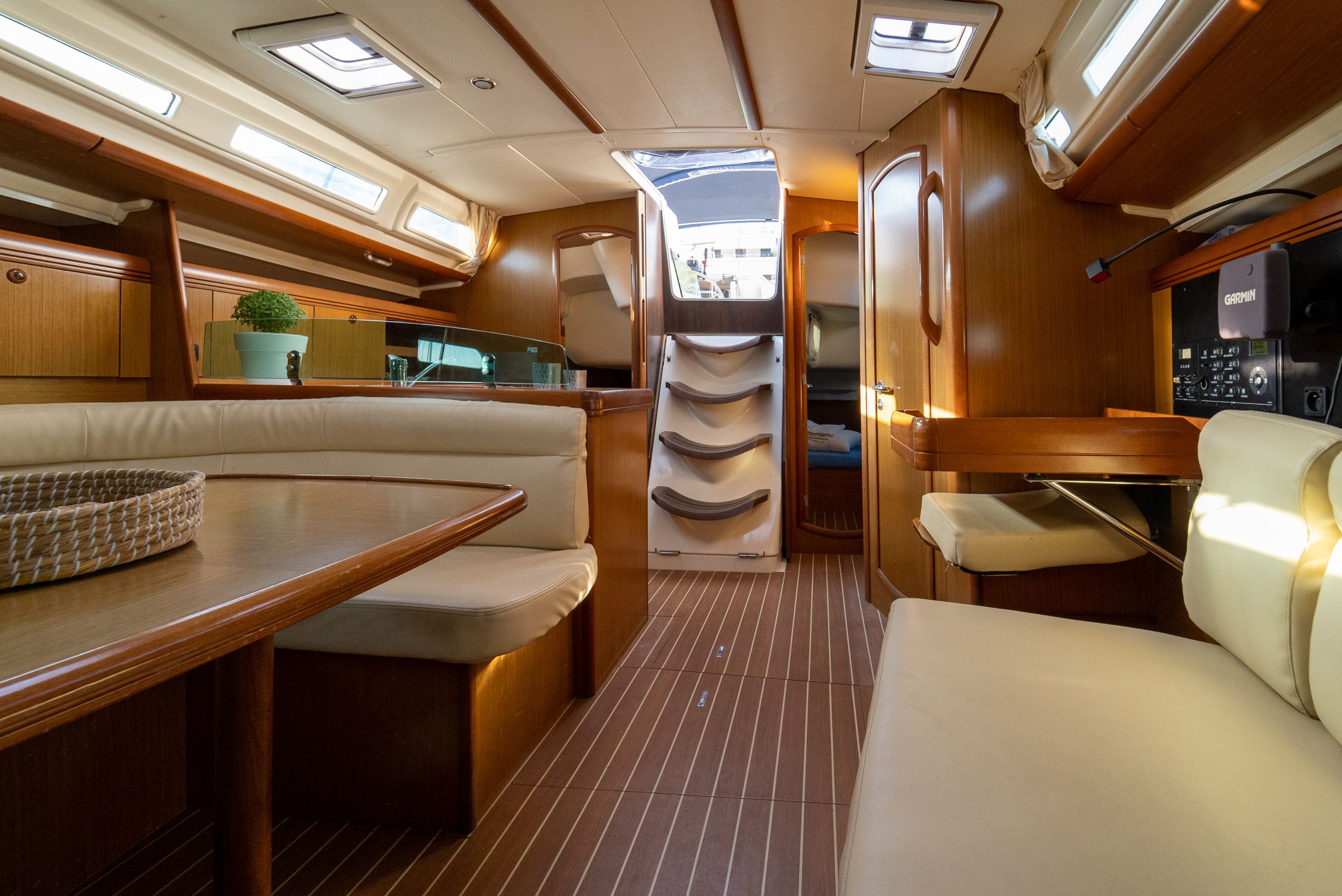 A well-lit interior of a boat with a dining area, seating, and a control panel.