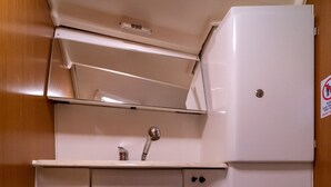 A compact bathroom with a toilet, a sink, and a storage cabinet. - Macedonian Sun and Beach Sailing Extravaganza from Kavala (Kavala)