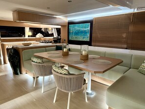 A modern interior with a dining area, kitchen, and seating. - Sun-Kissed Sailing Adventure in Islas Sarónicas (Alimos)