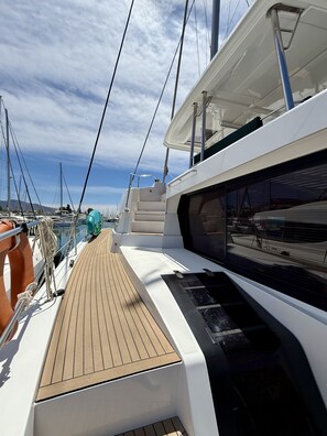 A yacht deck with a wooden floor, metal railings, and a white superstructure. - Sun-Kissed Sailing Adventure in Islas Sarónicas (Alimos)