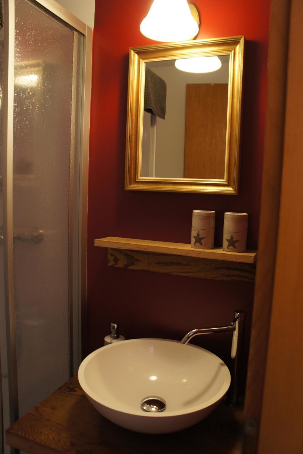 Ein Badezimmer mit einem weißen Waschbecken, einem Spiegel mit goldener Rahmung und einer Ablage mit zwei sternförmigen Behältern.