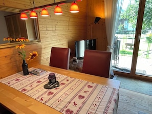 A wooden interior with a dining table, chairs, a vase with flowers, and a television. - Sweda EG Süd Appartement/Fewo, Dusche oder Bad, WC 2 Zimmerwohnung, 2-Betten by Interhome (Fiesch)