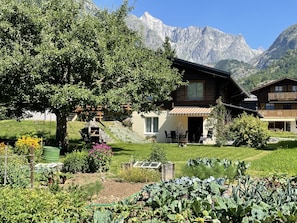 Eine Berghütte mit Garten, Sitzgelegenheiten im Freien und Blick auf die Berge.