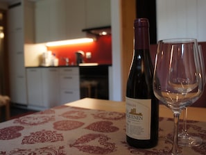 A bottle of wine and an empty glass on a table with a patterned tablecloth.