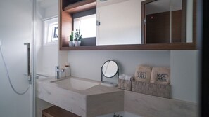 A bathroom with a large sink, a mirror, a towel rack with towels, and a potted plant. - Sun-Kissed Sailing Adventure in the Ionian Islands (Paleros)