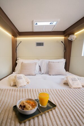 A hotel room with a bed, towels, a bowl of cereal, and a glass of orange juice. - Sun-Kissed Sailing Adventure in the Ionian Islands (Paleros)