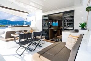 A yacht's interior with a dining area, a sofa, and a view of the sea. - Sun-Kissed Sailing Adventure in the Ionian Islands (Paleros)