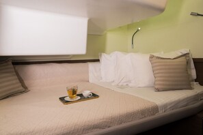Un lit simple avec un plateau contenant du thé et une tasse, un oreiller et une lampe de chevet.