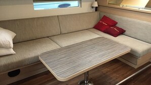 A compact living space with a sofa, a small table, and a window above the sofa. - Sun-kissed Sailing Adventure in Split-Dalmatia, Croatia (Trogir)