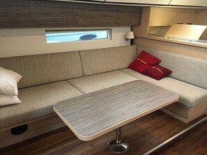 Ein kompakter Wohnbereich mit einer Couch, einem kleinen Tisch und einem Fenster über der Couch.