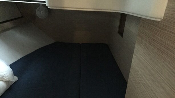 A bed with a dark mattress and a white pillow in a room with a wooden floor and a white wall. - Sun-kissed Sailing Adventure in Split-Dalmatia, Croatia (Trogir)