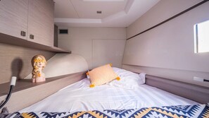 A bedroom with a bed, a headboard, a shelf with a decorative item, and a window. - Sun-Kissed Sailing Adventure in the Ionian Islands, Lefkada (Lefkada)