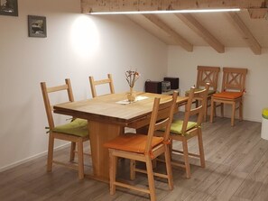 Ein Essbereich mit einem Holztisch und Stühlen, einer kleinen Pflanze auf dem Tisch und einer Deckenleuchte.