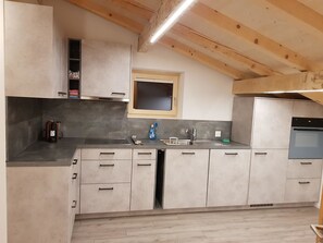 A kitchen with a built-in oven, a window, and a wooden ceiling. - Lischa 3. OG Süd Appartement/Fewo, Dusche oder Bad, WC by Interhome (Fiesch)