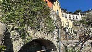 Uma ponte de pedra com arco, um banco e um caminho de cascalho.